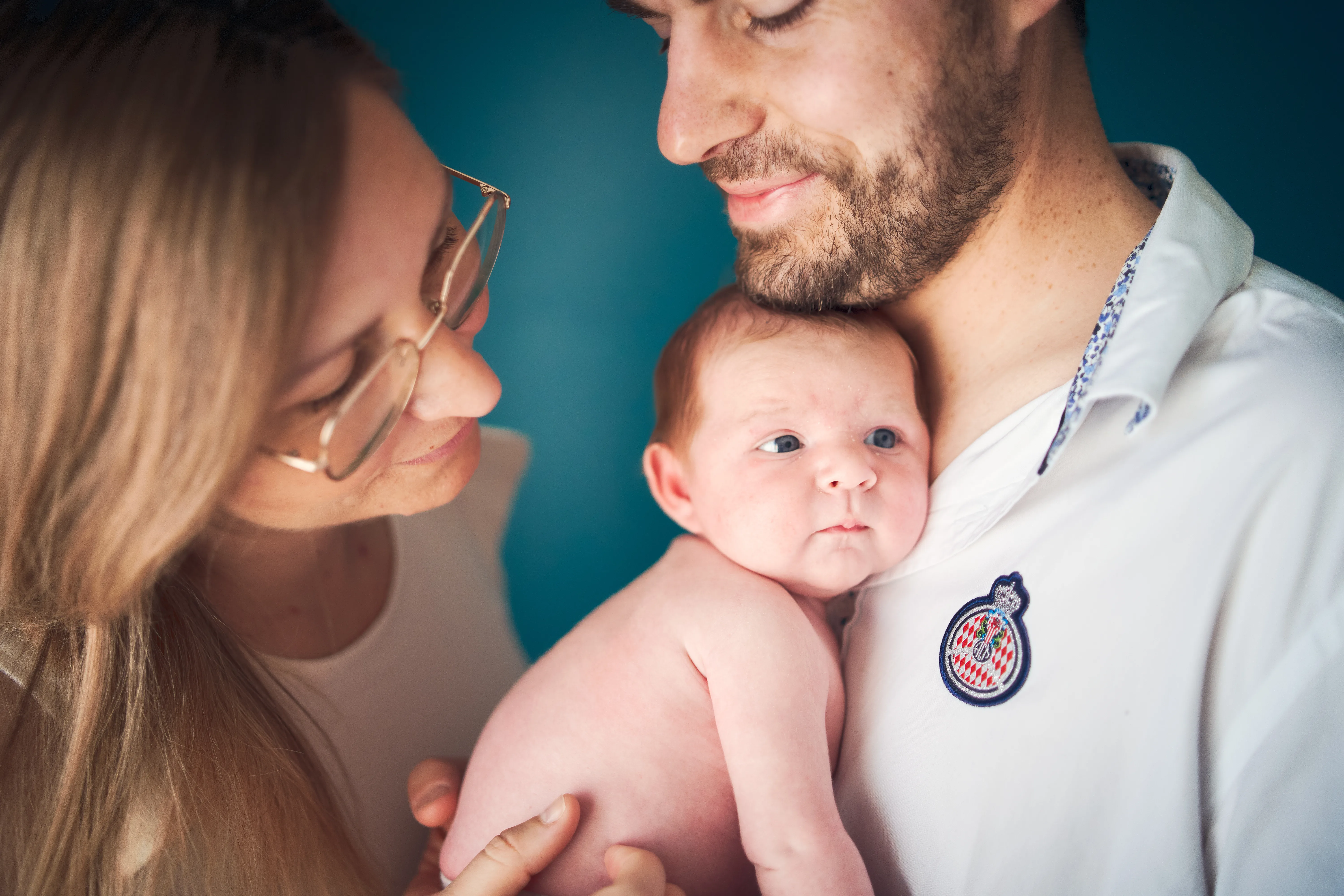 Parents entourant leur bébé éveillé dans leurs bras.
