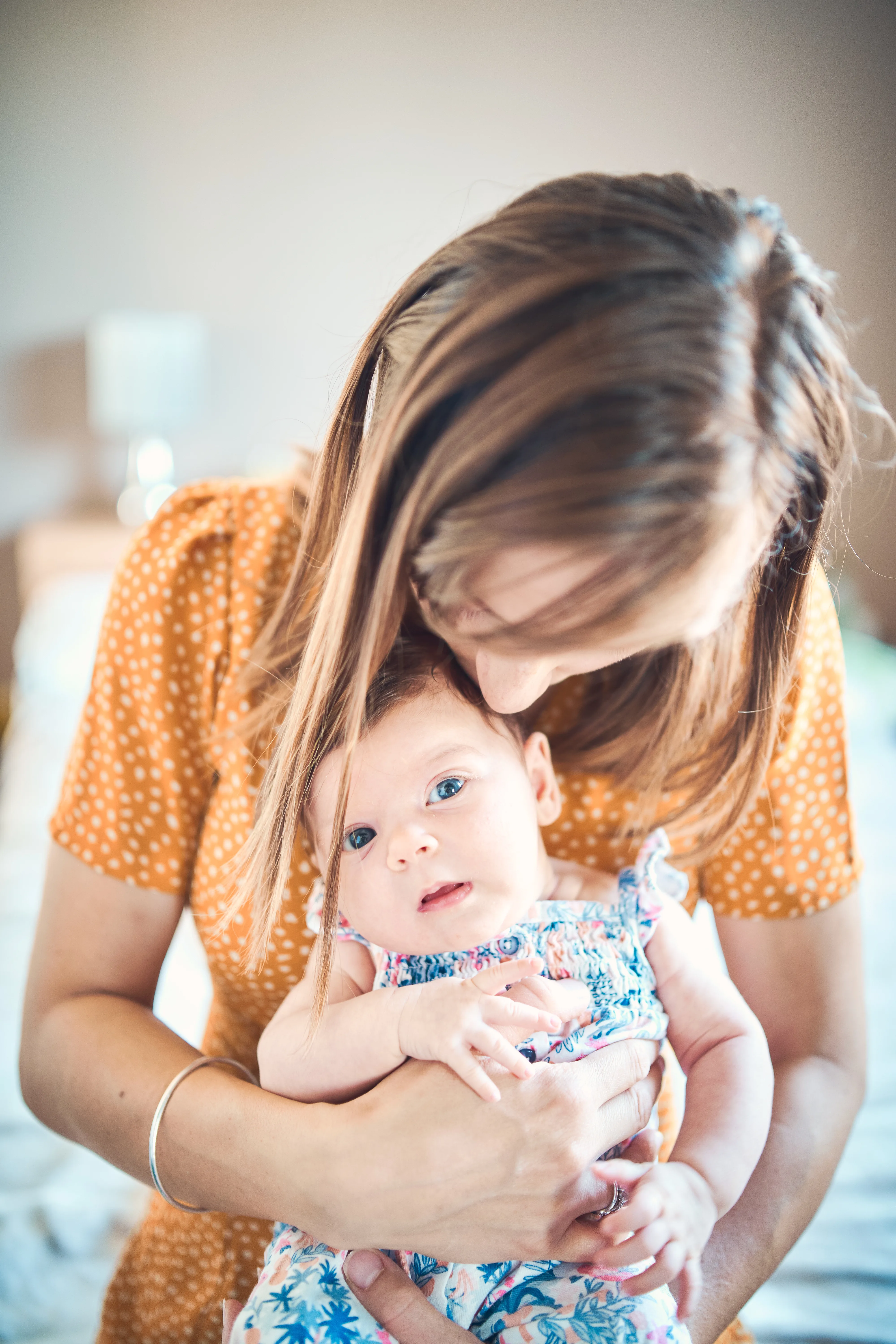 Mère tenant son bébé contre elle pendant une séance naissance à domicile.