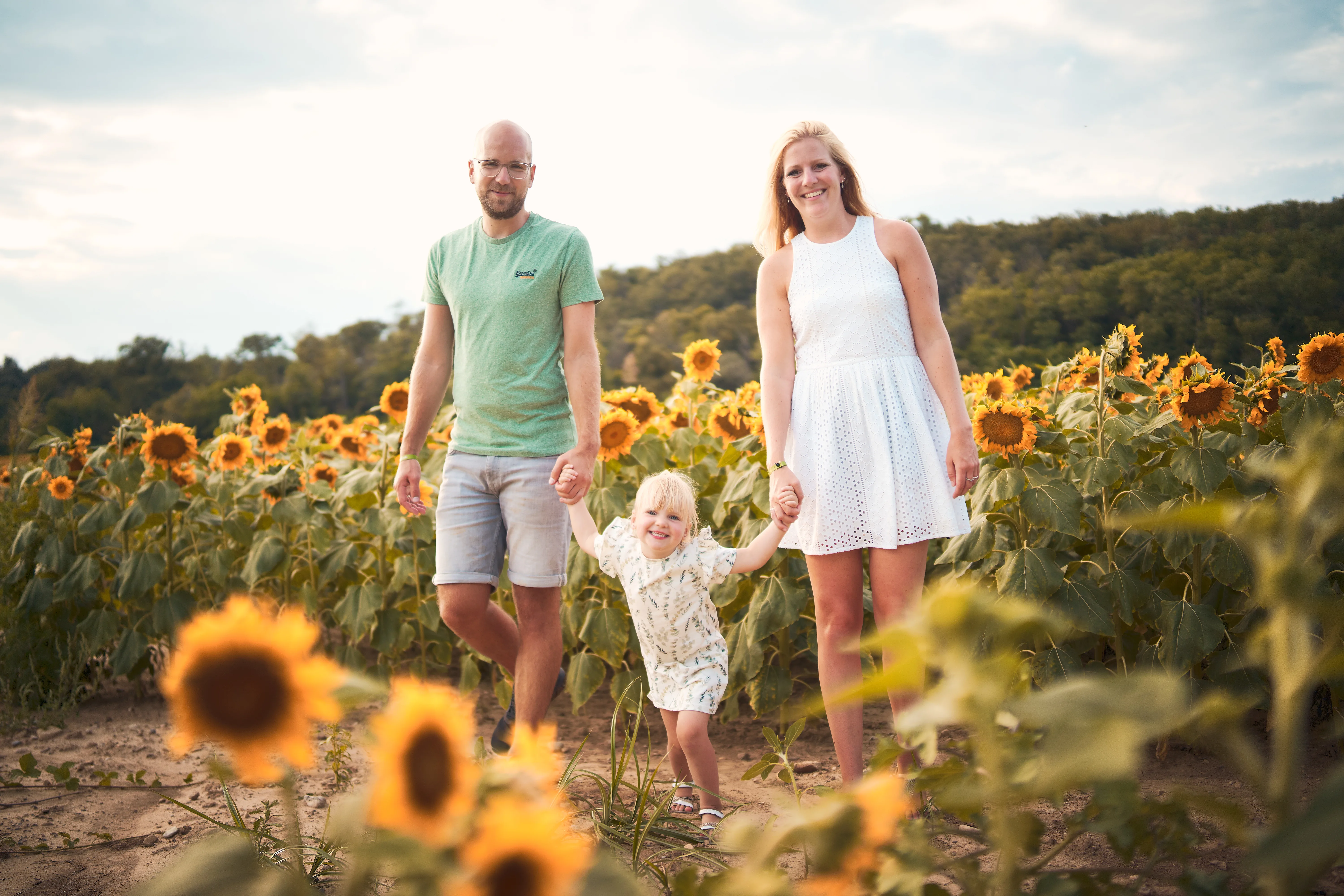 Parents marchant avec leur enfant entre les tournesols.