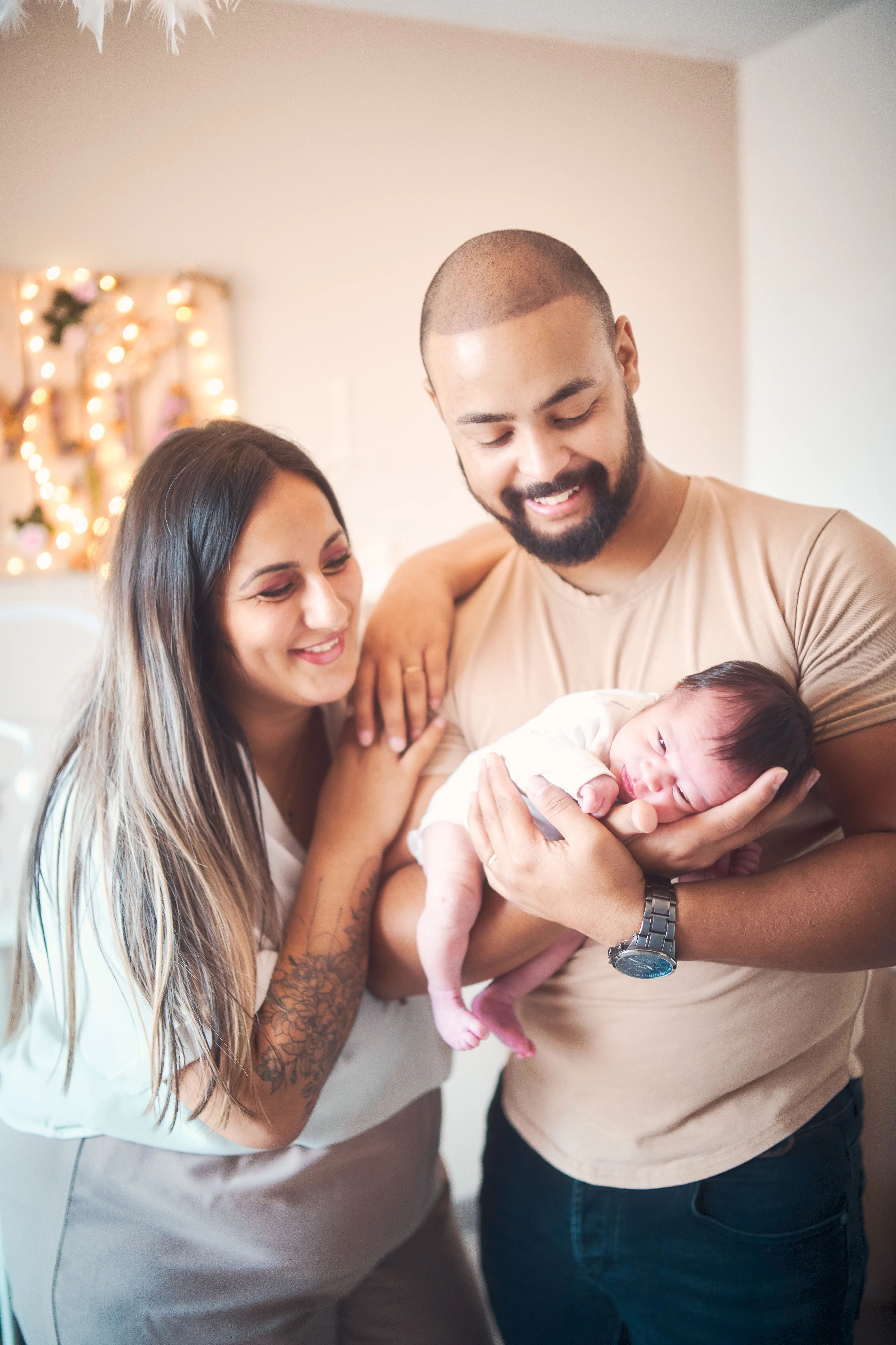 Parents souriants tenant leur nouveau-né à la maison.