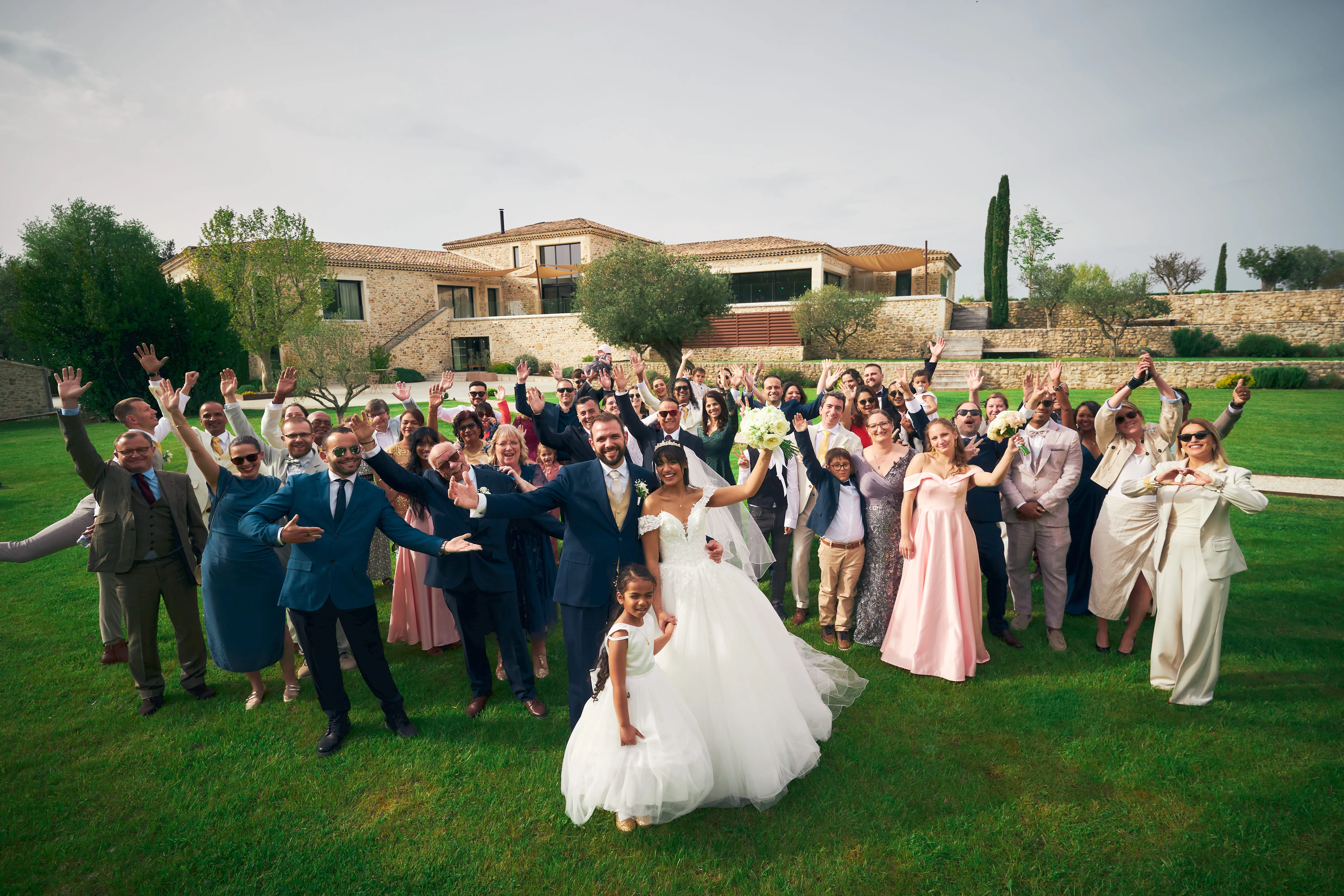 Mariés et invités réunis dans le jardin d'un domaine.