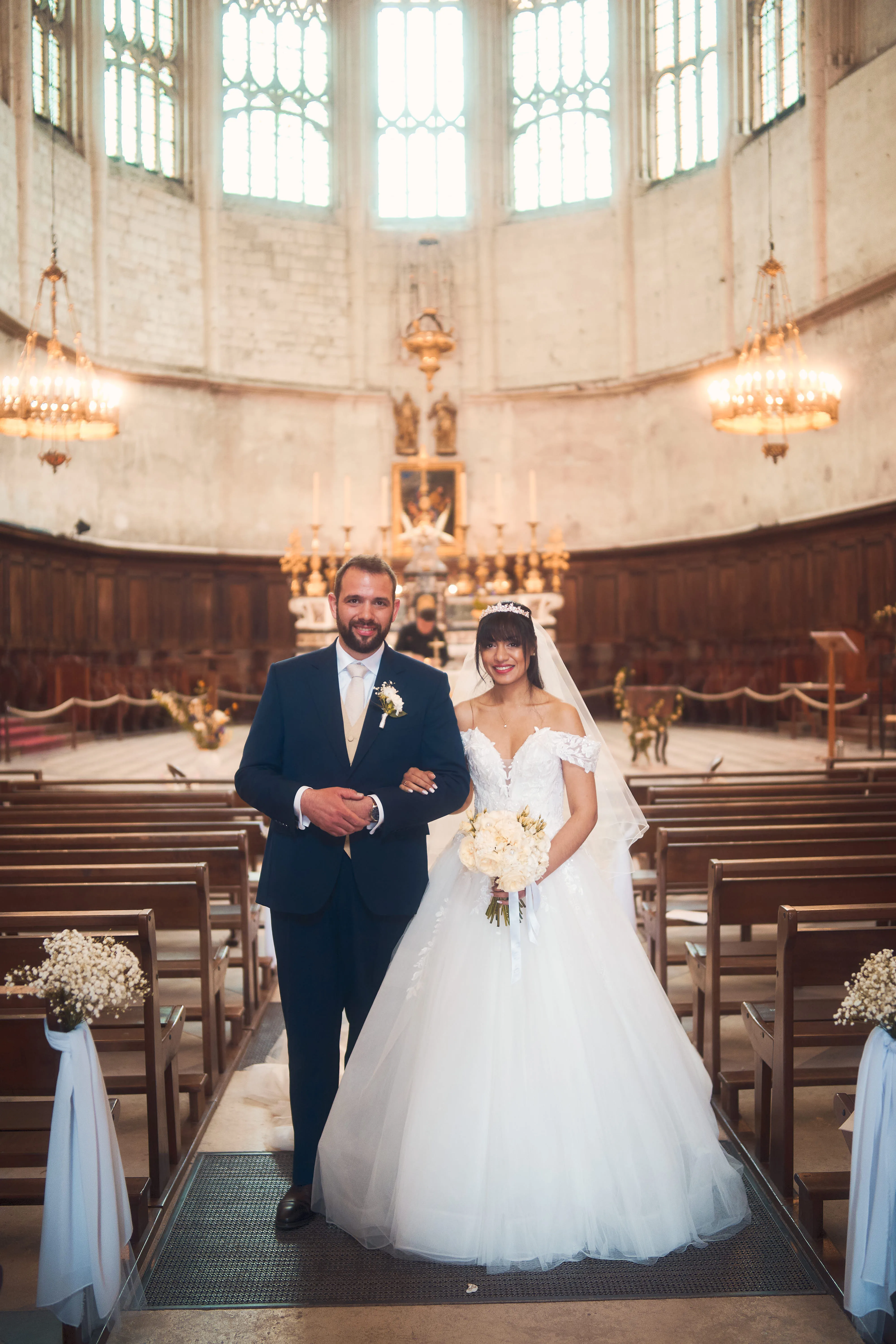 Mariés dans une église éclairée par un lustre.