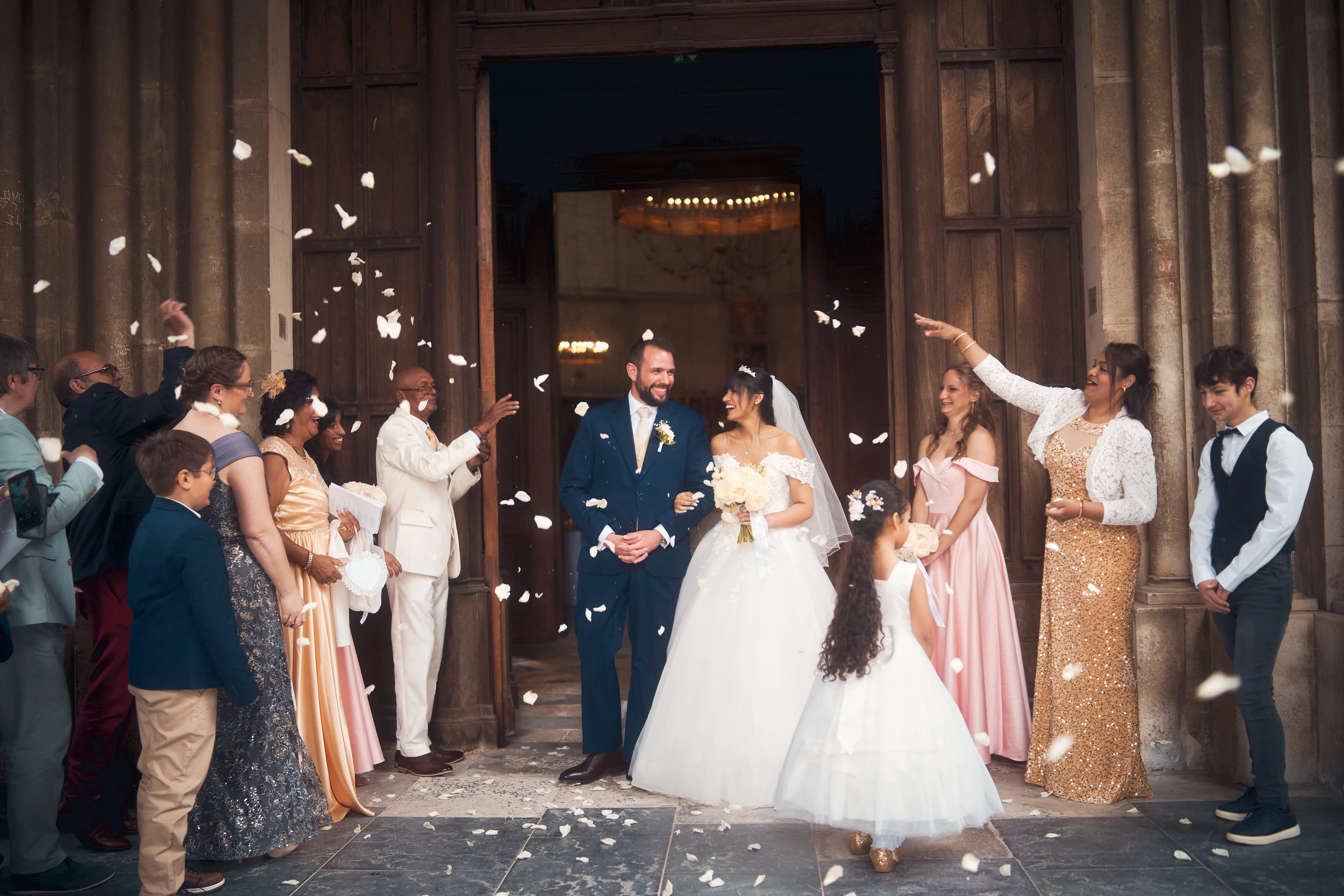 Mariés et invités à la sortie d'une église sous une pluie de confettis.