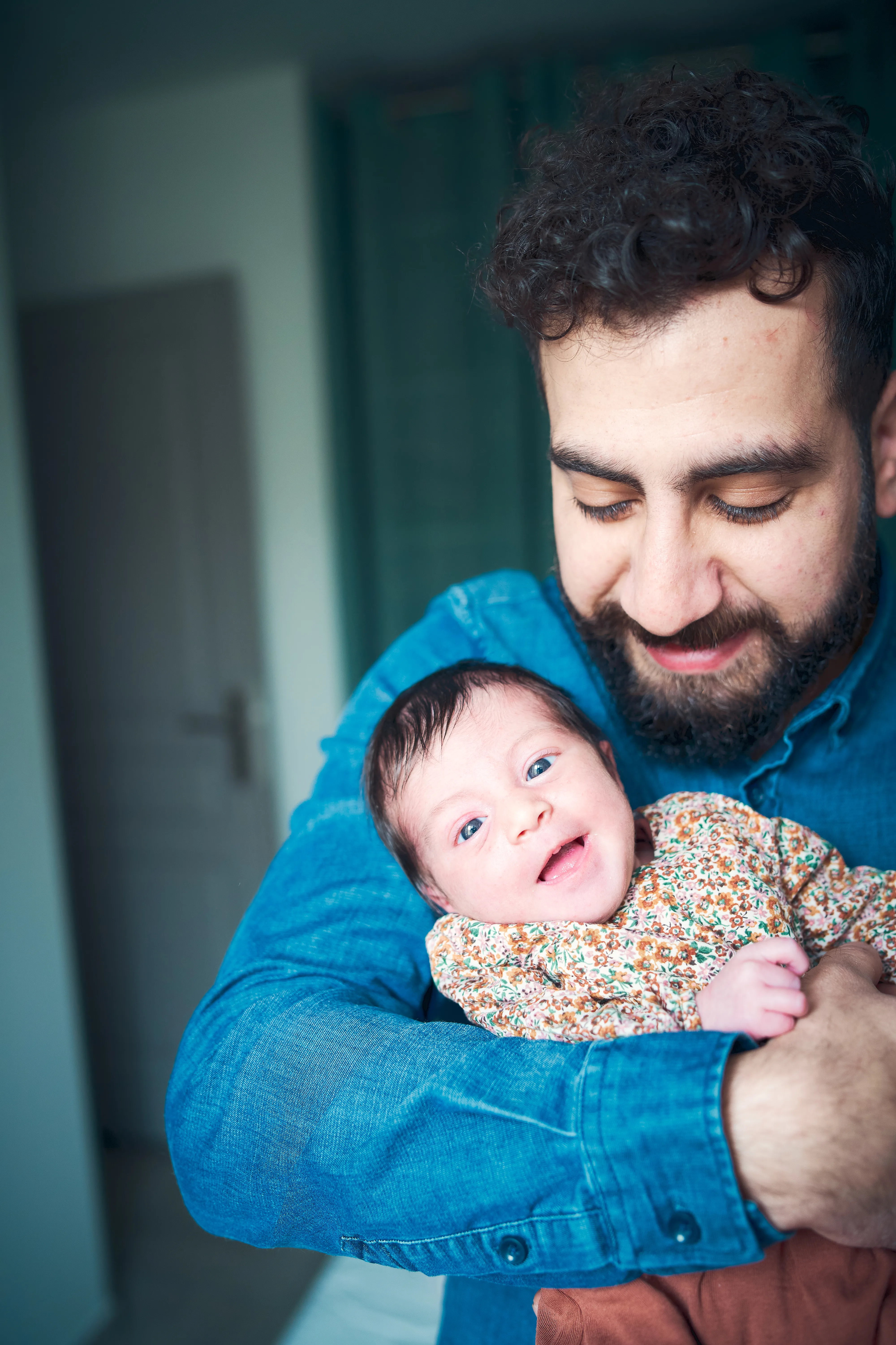 Père tenant son bébé endormi dans ses bras à la maison.