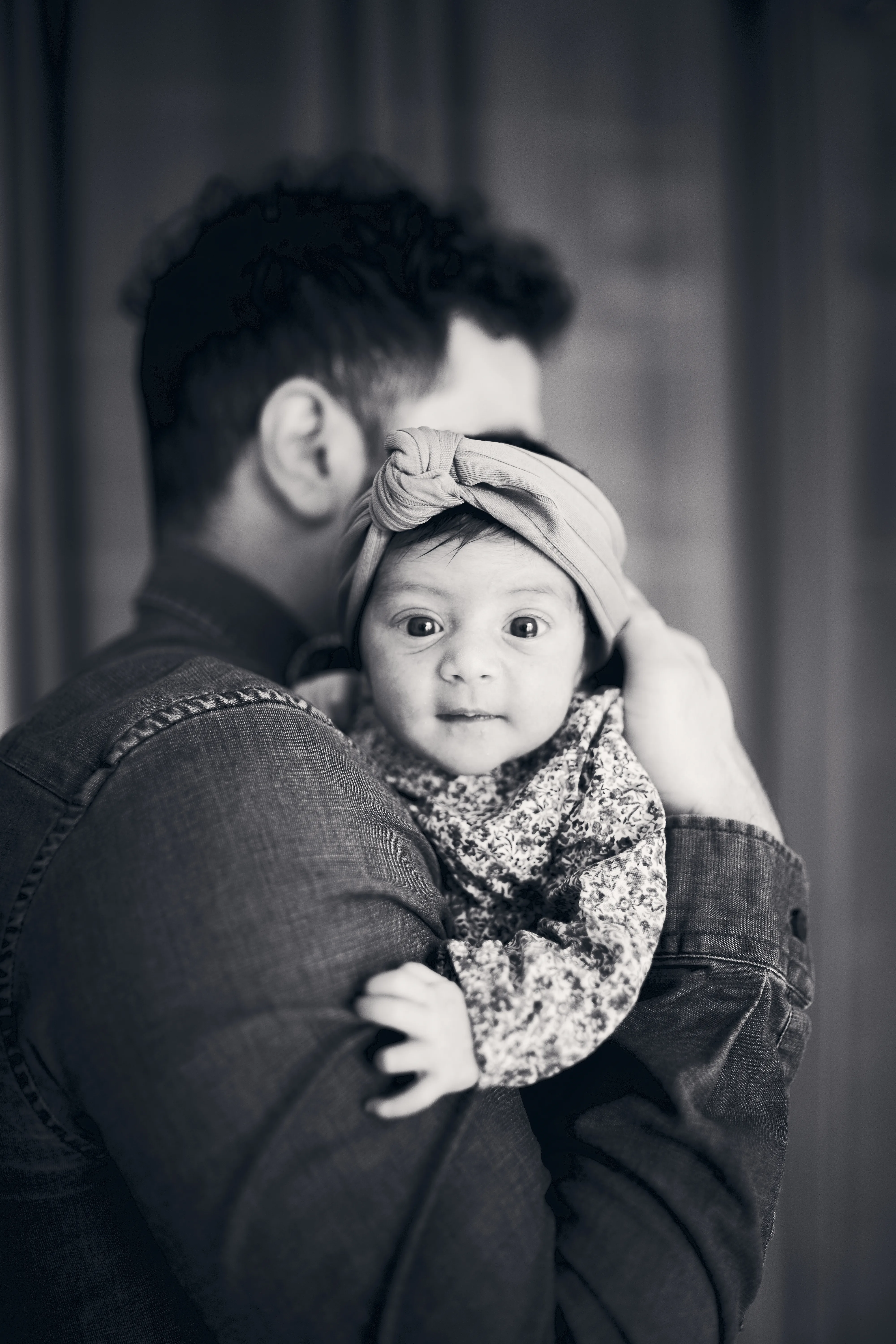 Bébé photographié dans les bras pendant un reportage à domicile.