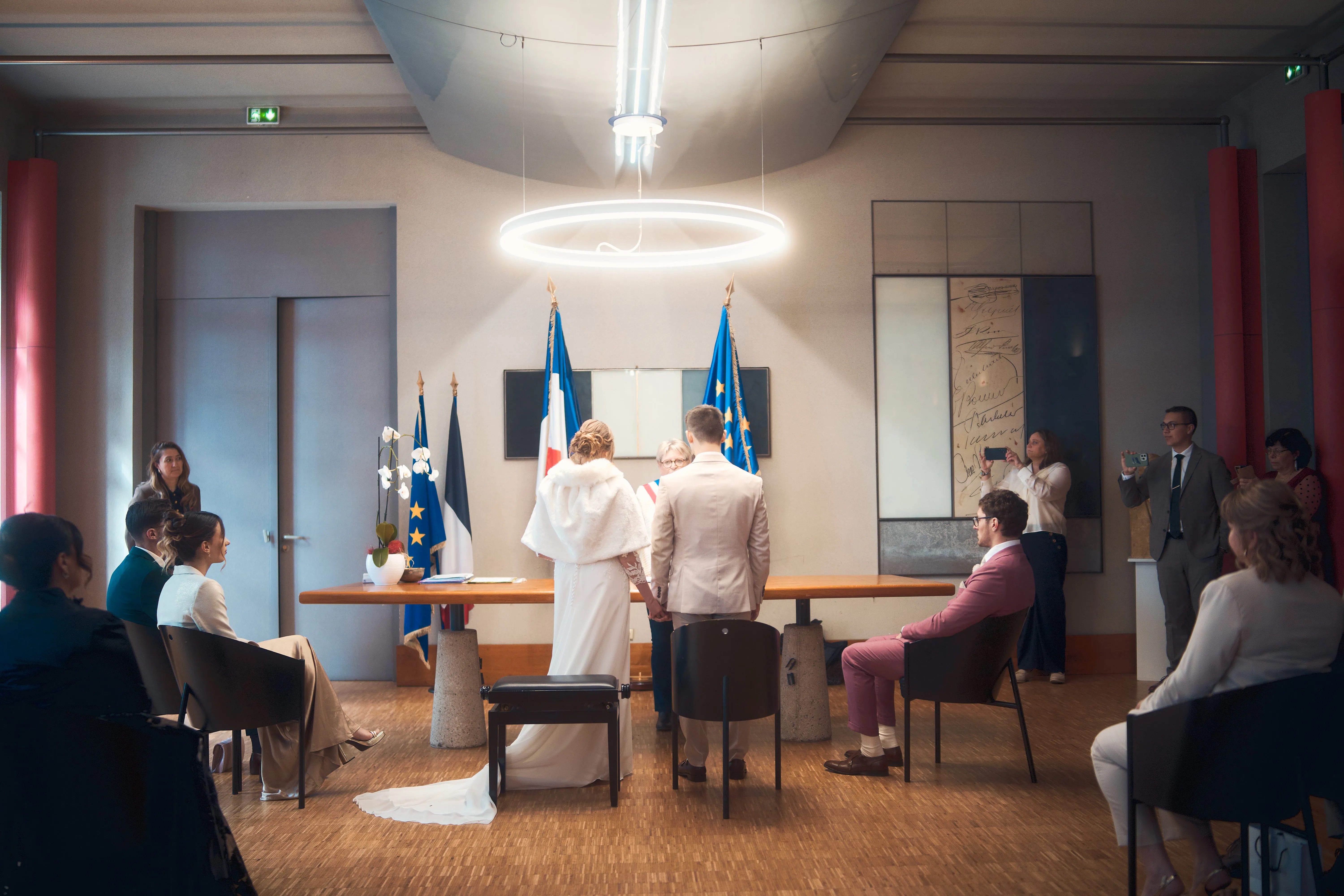 Cérémonie civile dans une salle de mairie, entourée des proches des mariés.