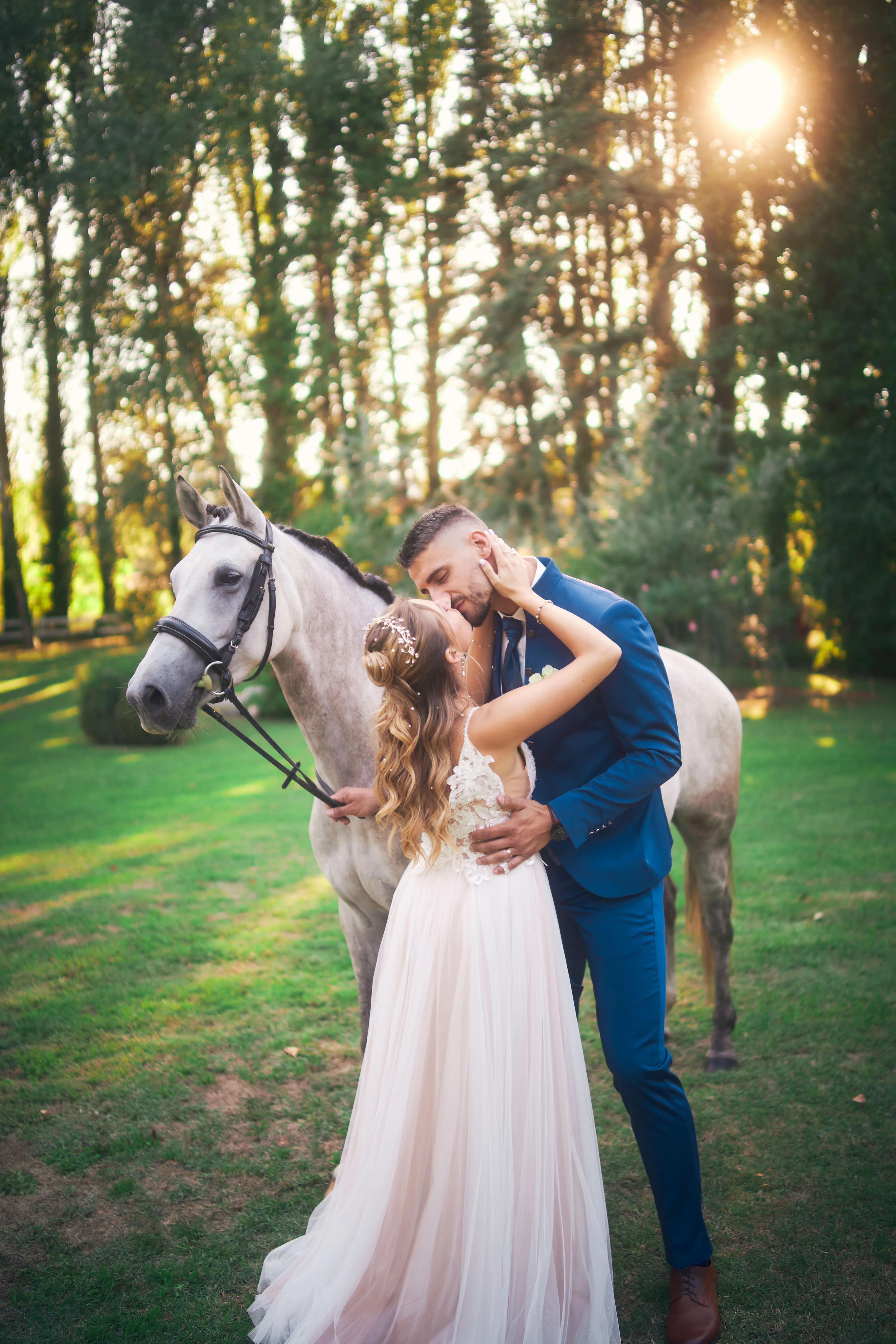 Mariés posant avec un cheval dans un parc.