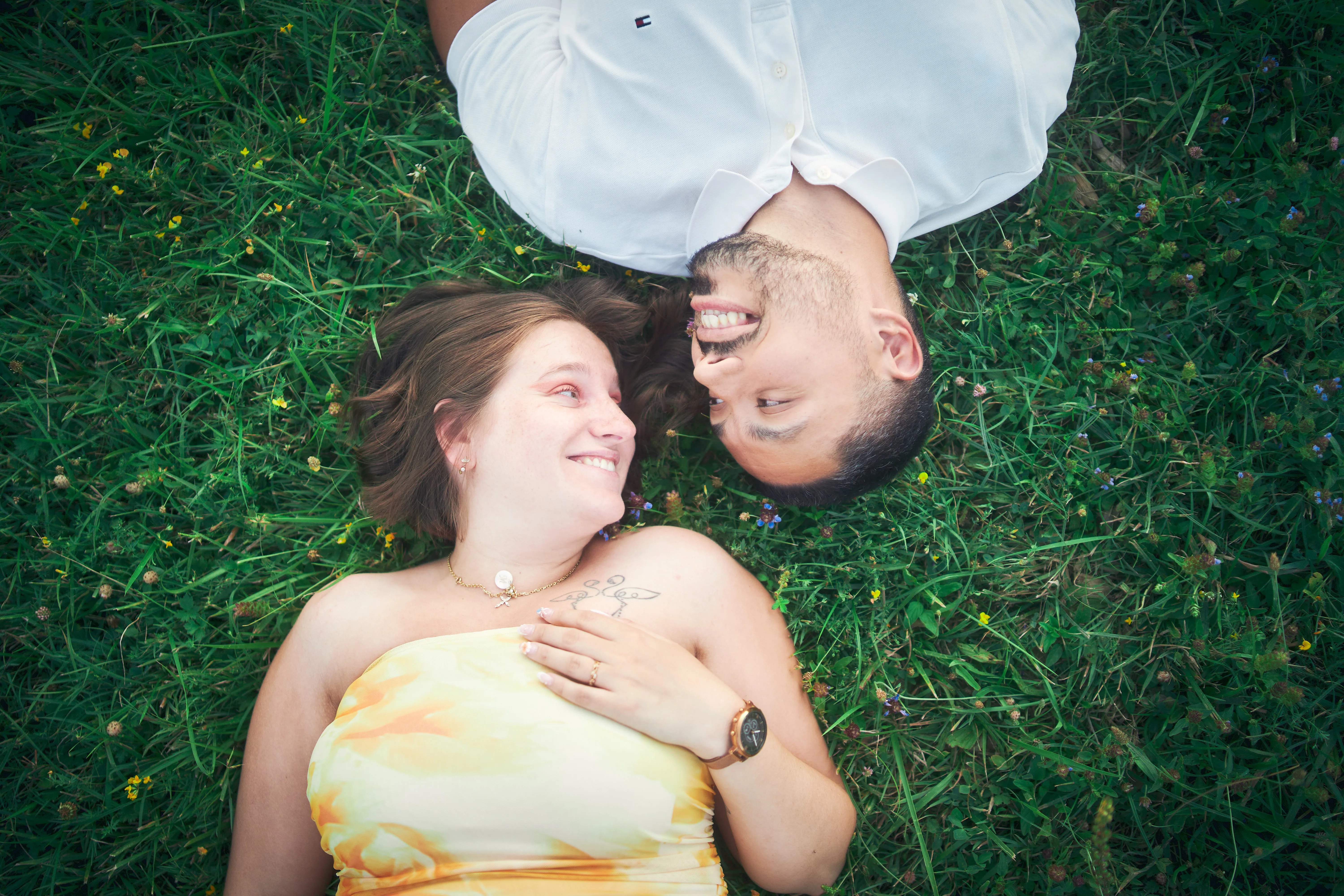 Femme enceinte allongée dans l'herbe, son compagnon penché vers elle.